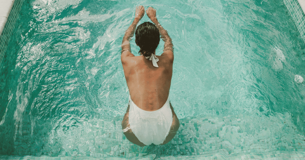 woman in white bathing swimming about to jump in pool