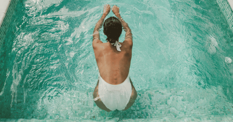 woman in white bathing swimming about to jump in pool
