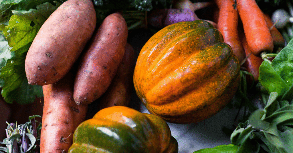 Fresh fall vegetables including sweet potatoes, squash, and carrots arranged together - seasonal foods that boost immune system for fall wellness.