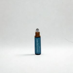 Grounded essential oil roller with teal label and amber glass bottle on white background