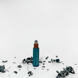 Breathe Easy essential oil roller in teal with amber glass bottle surrounded by dried eucalyptus leaves on white background